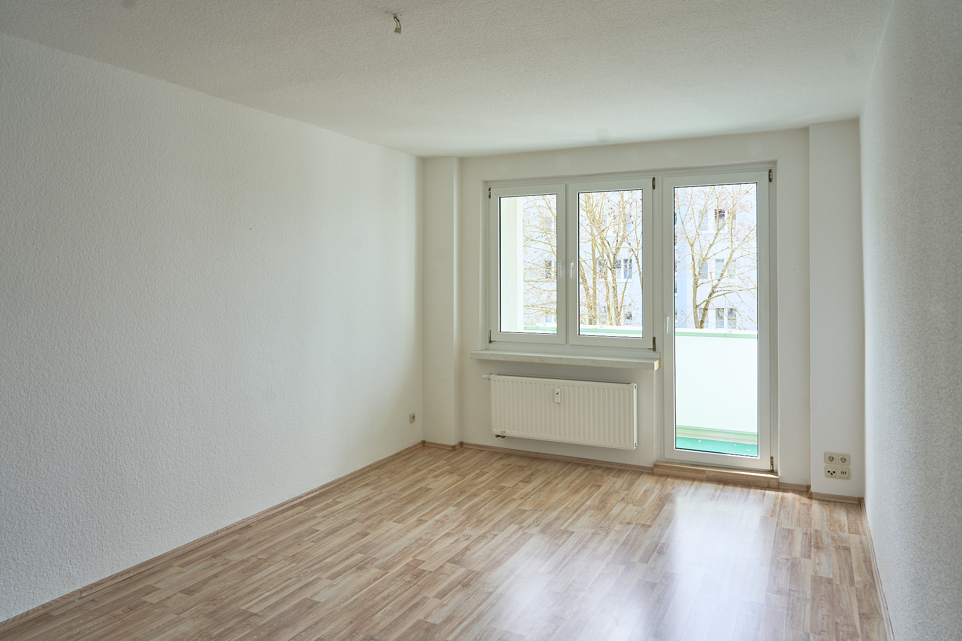 Helles Wohnzimmer mit Laminatboden und Balkontür